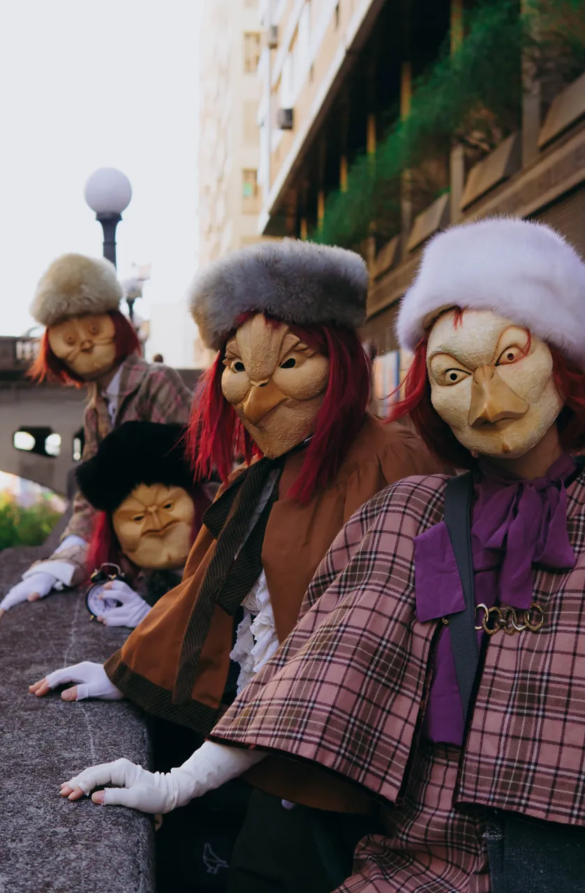 Figuras mascaradas de chapéu de pele debruçadas num parapeito, de perto